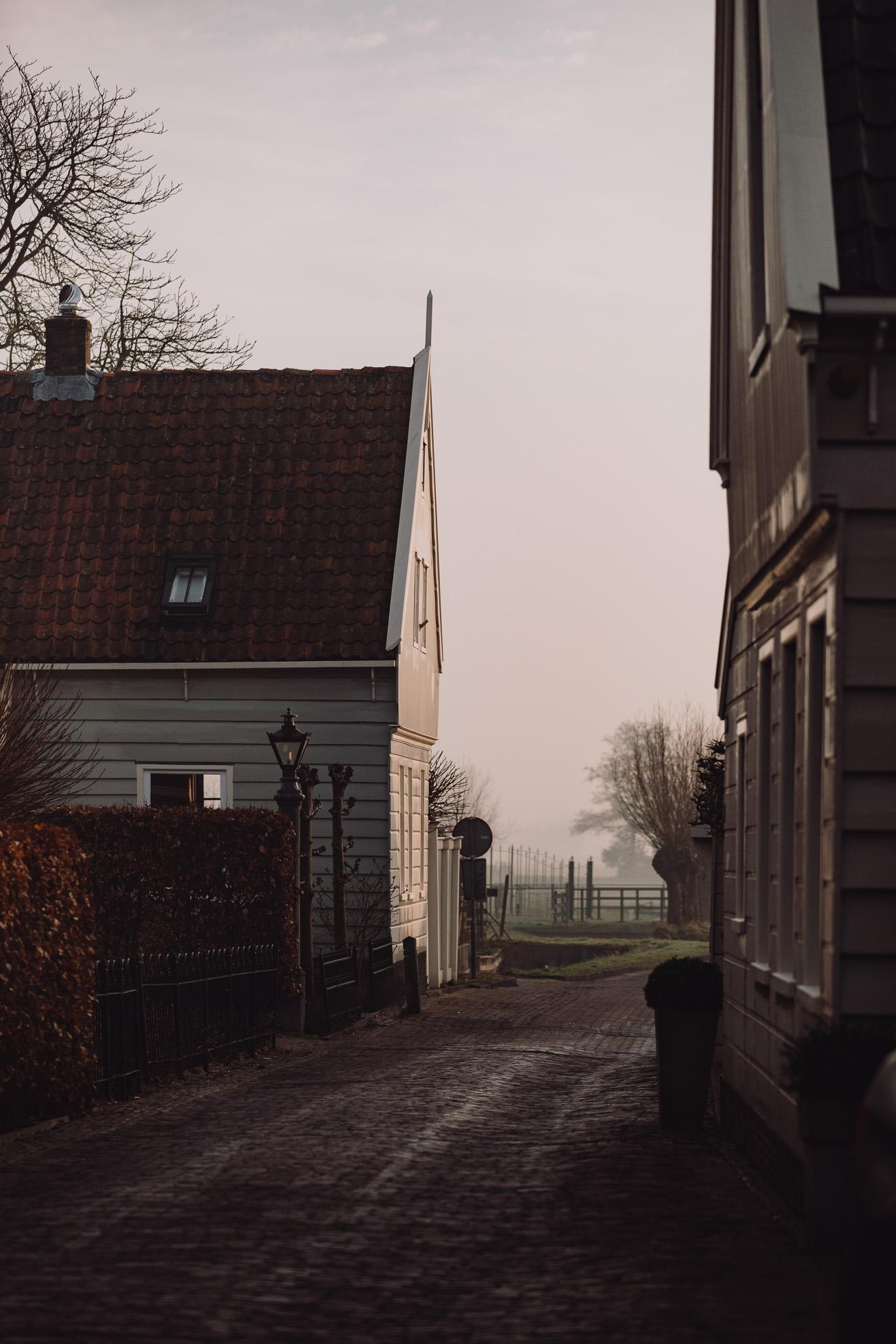 Groene en grijze houten huizen en water in Broek in Waterland – rustgevend uitzicht ochtenddauw