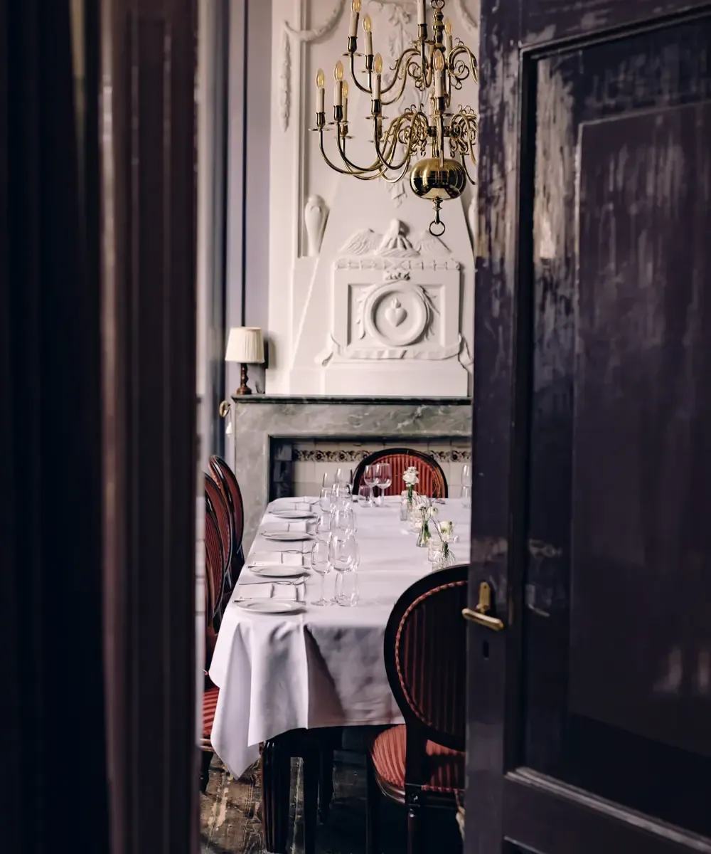 Strak wit gedekte tafel met kroonluchter in de Regentessenkamer – trouwlocatie Broek in Waterland