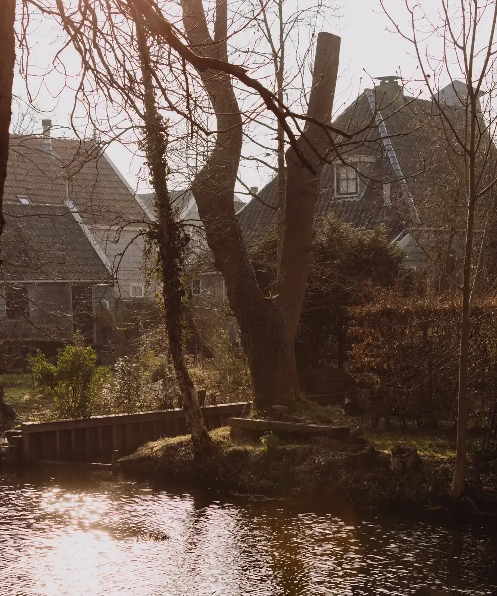 Zonlicht door bomen op water en huizen Broek in Waterland